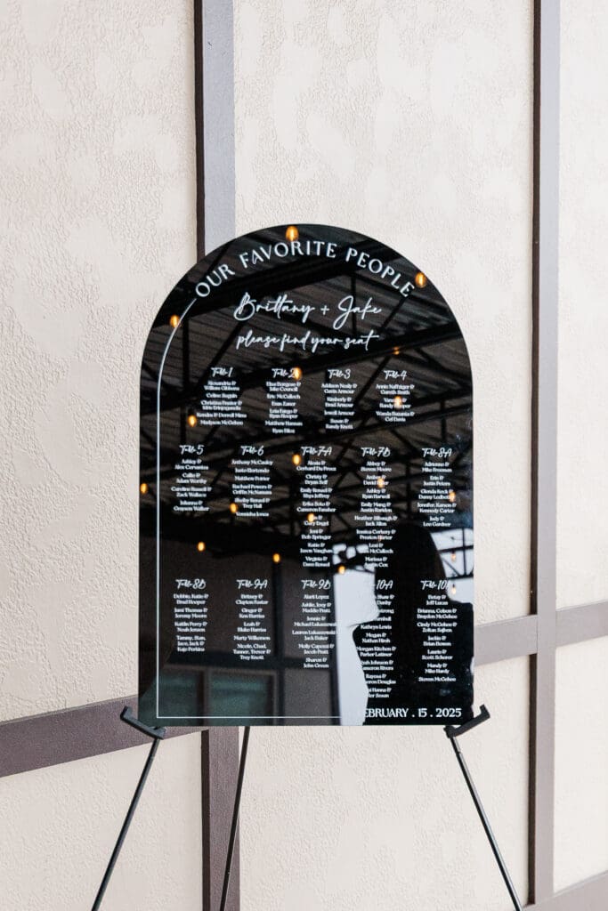 Detail of black acrylic seating chart with guest names and table numbers. 
