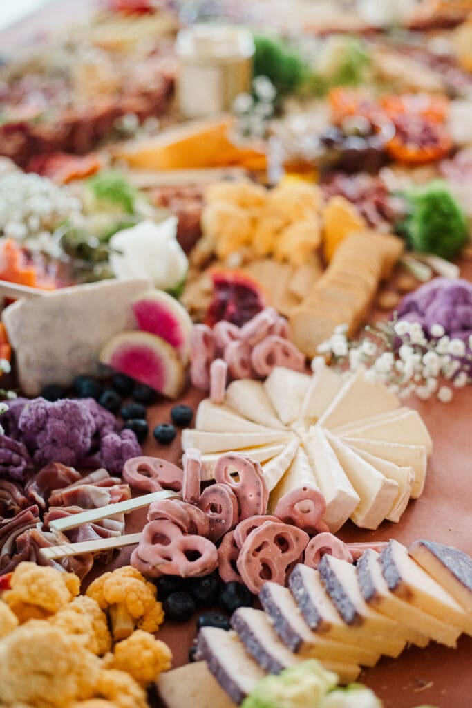 Close-up of colorful charcuterie board with cheeses, fruits, and crackers for wedding cocktail hour.