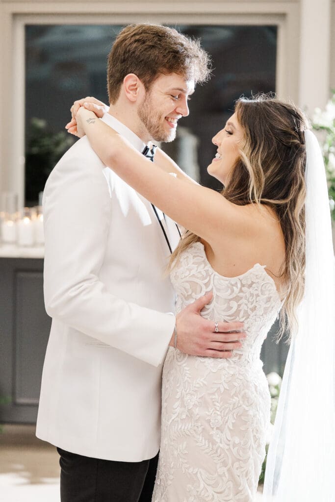 Smiling couple embraces on the dance floor during their wedding reception.