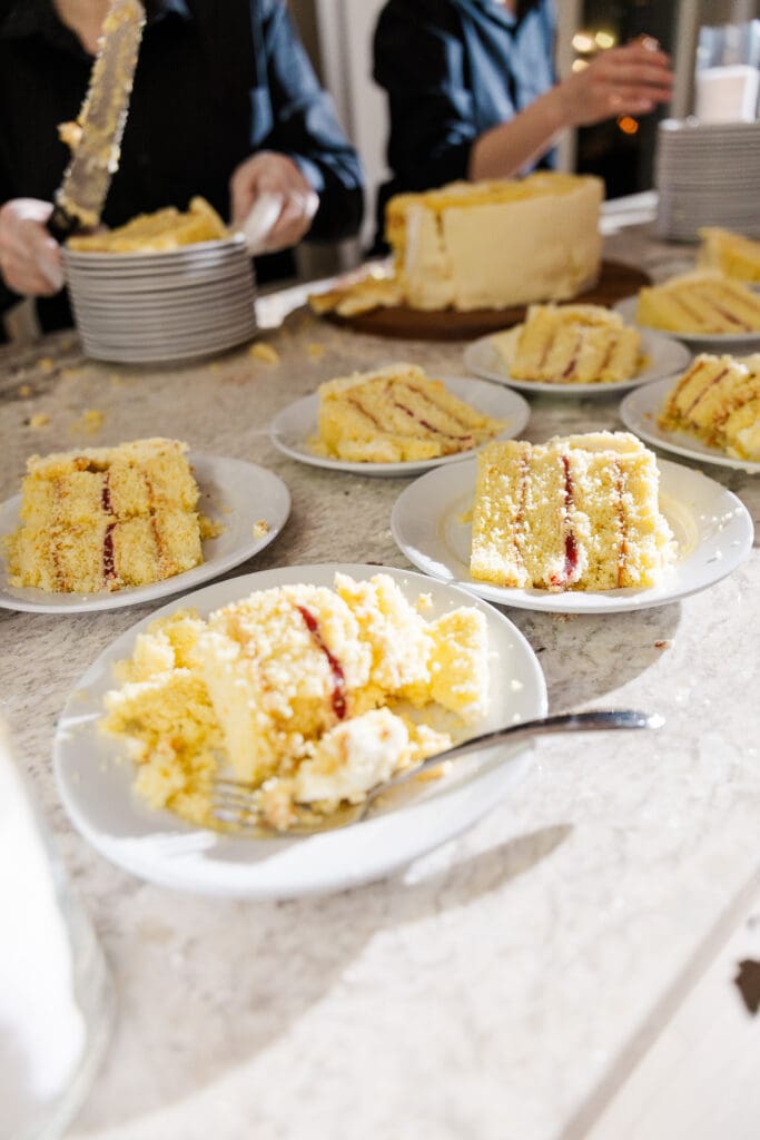 Wedding cake slices plated and ready to serve on marble countertop during reception dessert hour.