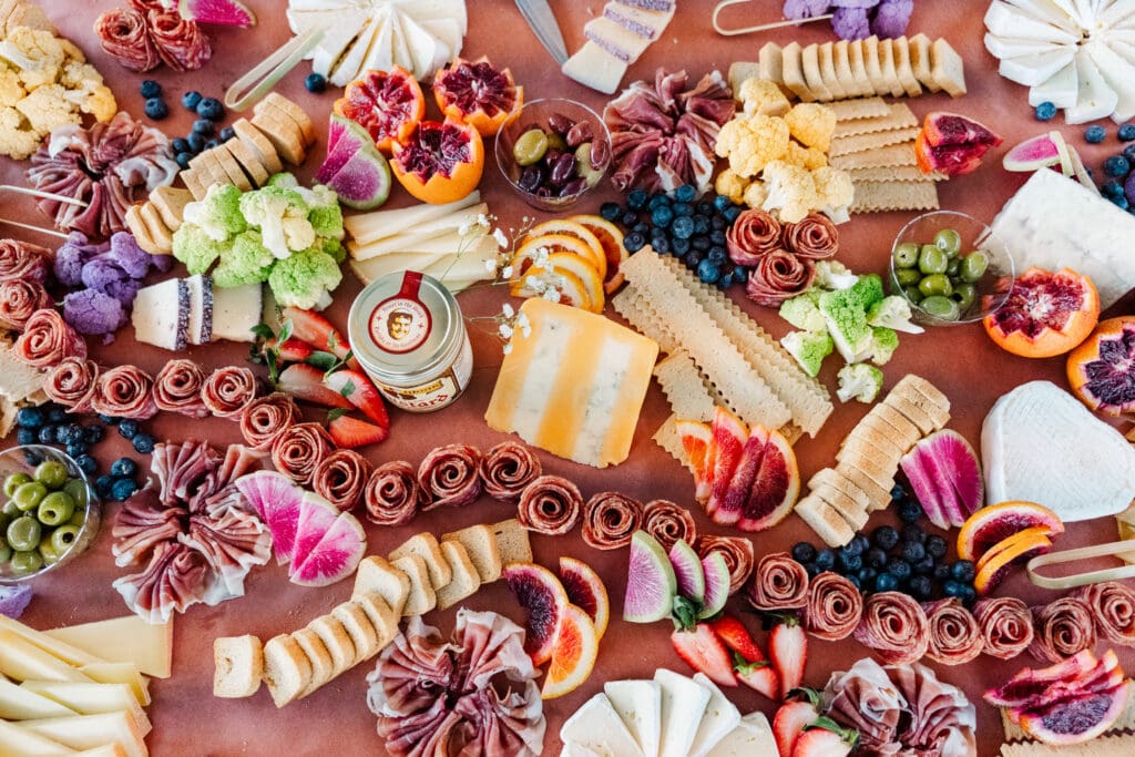 Colorful charcuterie spread with meats, cheeses, fruits, and crackers styled for wedding cocktail hour.