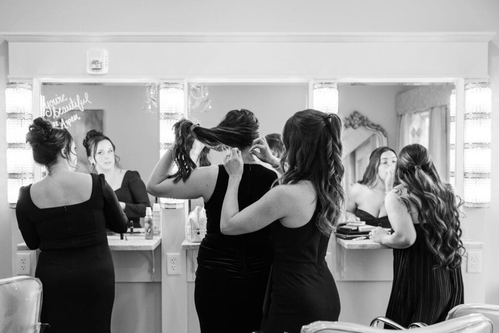 Bridesmaids fixing hair and makeup in bridal suite mirrors before the ceremony