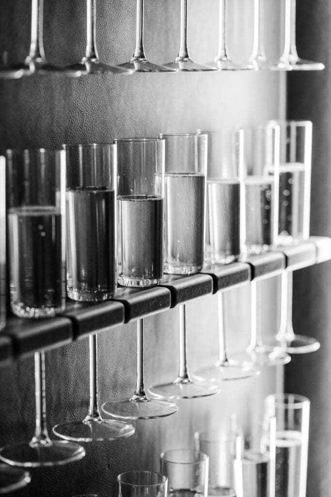 Black and white detail of champagne glasses filled and arranged on a display wall