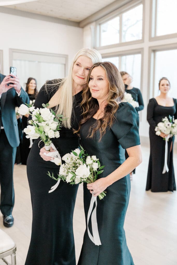 Mother of the bride and mother of the groom share a tearful embrace as they watch the bride walk down the aisle. Photo by Shanle Bowen Photography, an ATL wedding photographer.