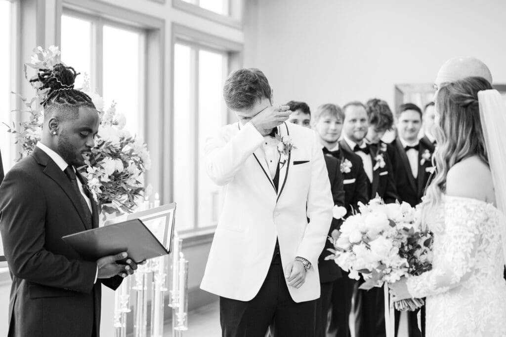 Atlanta wedding photographer Shanle Bowen captures groom wiping tears as bride walks down the aisle toward him.