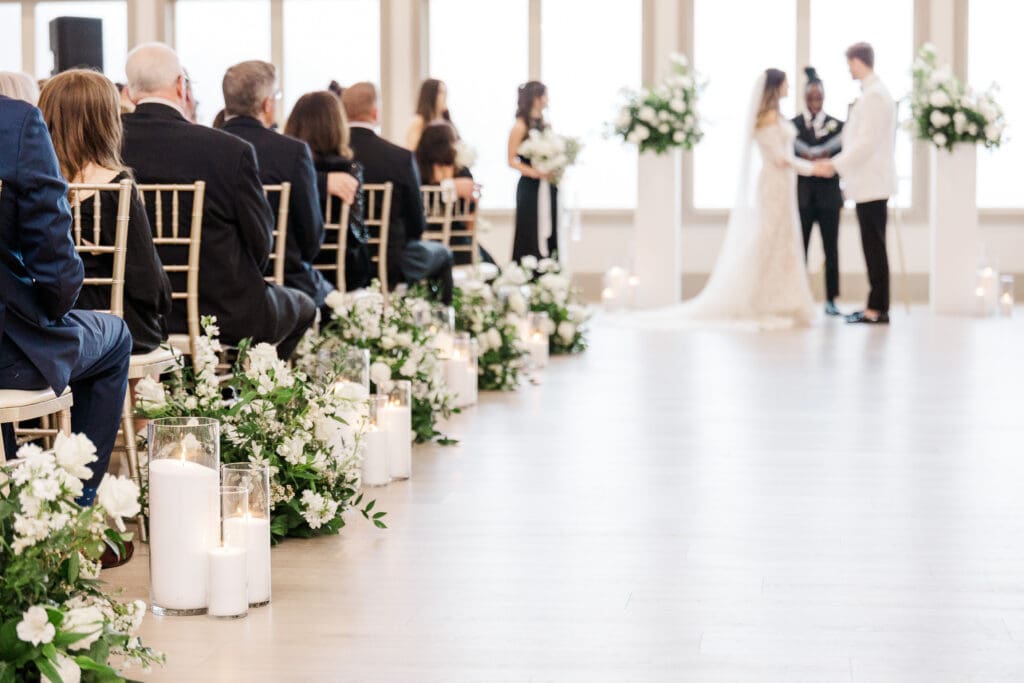 North Georgia wedding photographer captures indoor ceremony with aisle flowers and candles at Venue In The Vines.