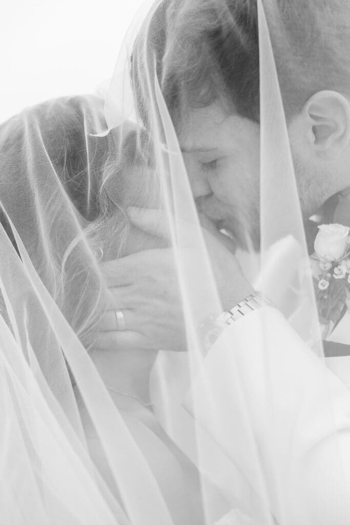 Romantic black and white portrait of bride and groom kissing under veil. Photo by Atlanta wedding & engagement photographer Shanle Bowen.